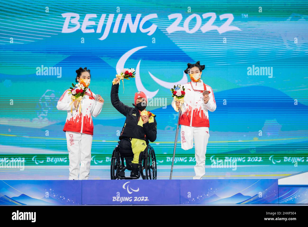 Peking, China. 12th Mar, 2022. Paralympics, Para Alpine Skiing, women, slalom, sitting, award ceremony Yanqing Medals Plaza: Haiyuan Zhang of China (l-r), 2nd place, Anna-Lena Forster of Germany, 1st place, and Sitong Liu of China, 3rd place. Credit: Christoph Soeder/dpa/Alamy Live News Stock Photo