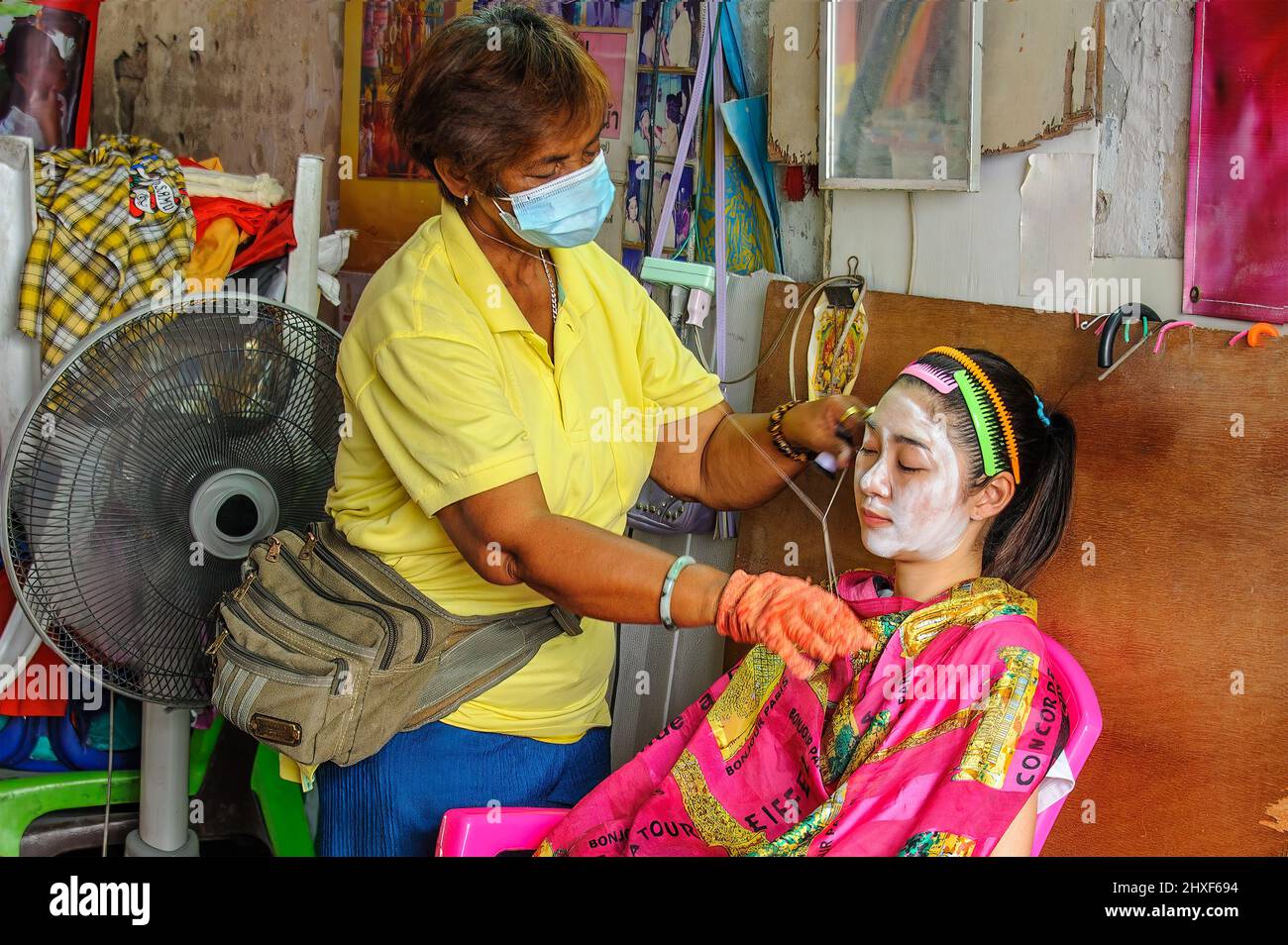 Chinatown, Bangkok – Nov, 14, 2020: Ancient Chinese method of removing facial hair using two threads to squeeze and pull. Stock Photo