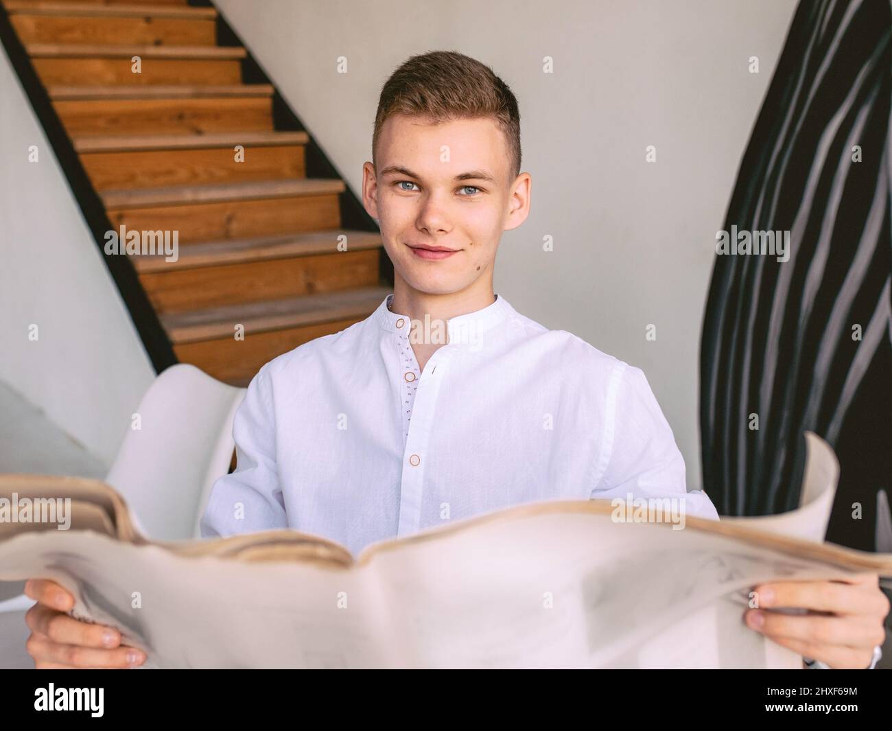 Modern teen man reading paper newspaper while breakfast at home. Reading, old fashion, modern, news concept Stock Photo