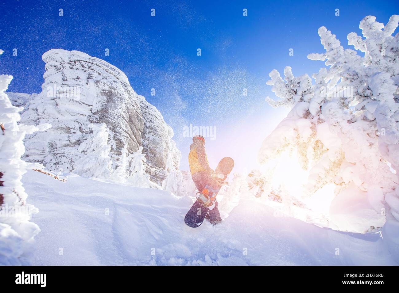 Snowboarder with snowboard background blue sky with sun light frozen rocks, Sheregesh ski resort. Concept extream freeride on fresh snow. Stock Photo