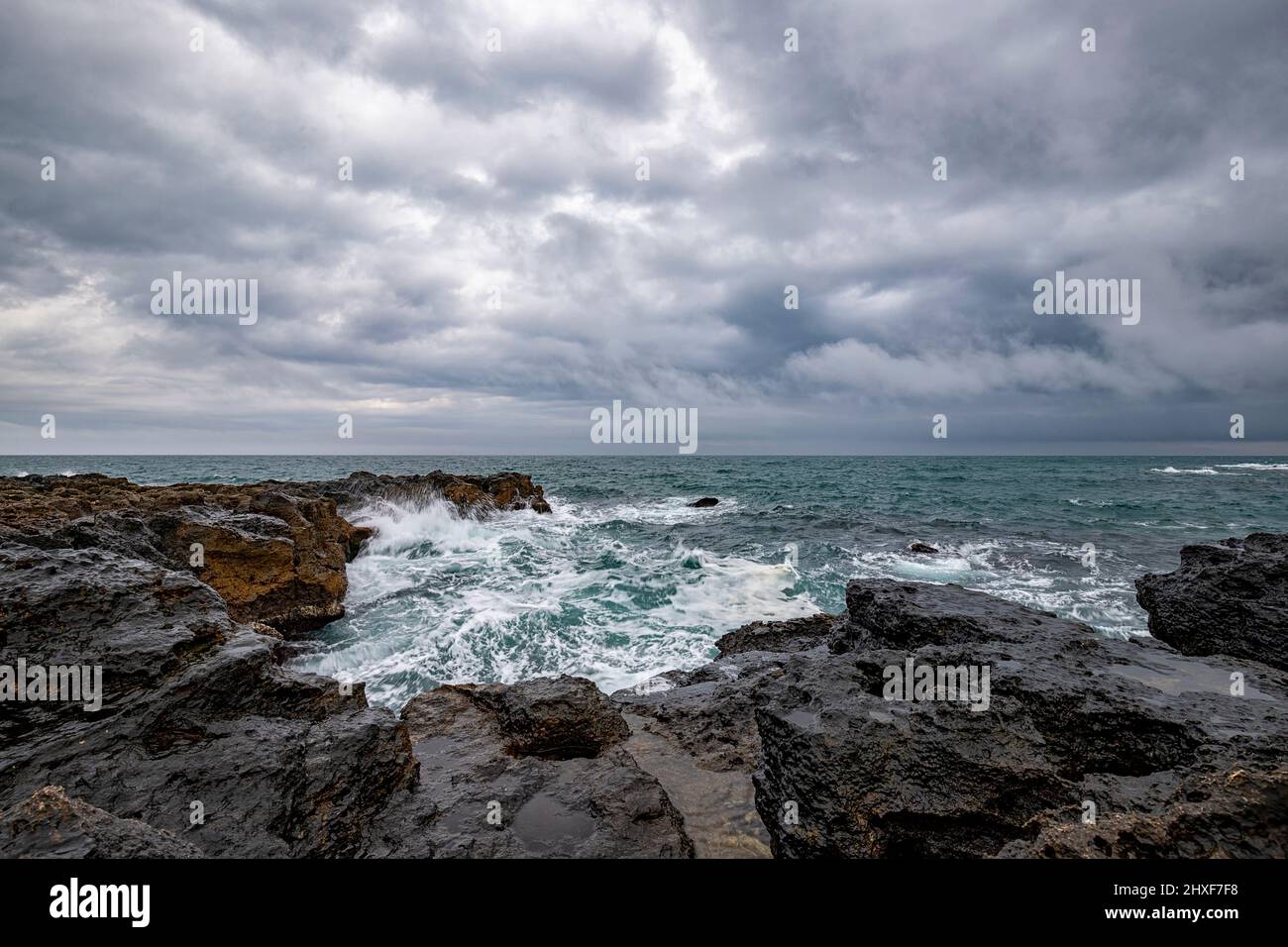 Stunning seascape with scenic clouds over the sea with rocky shore Stock Photo