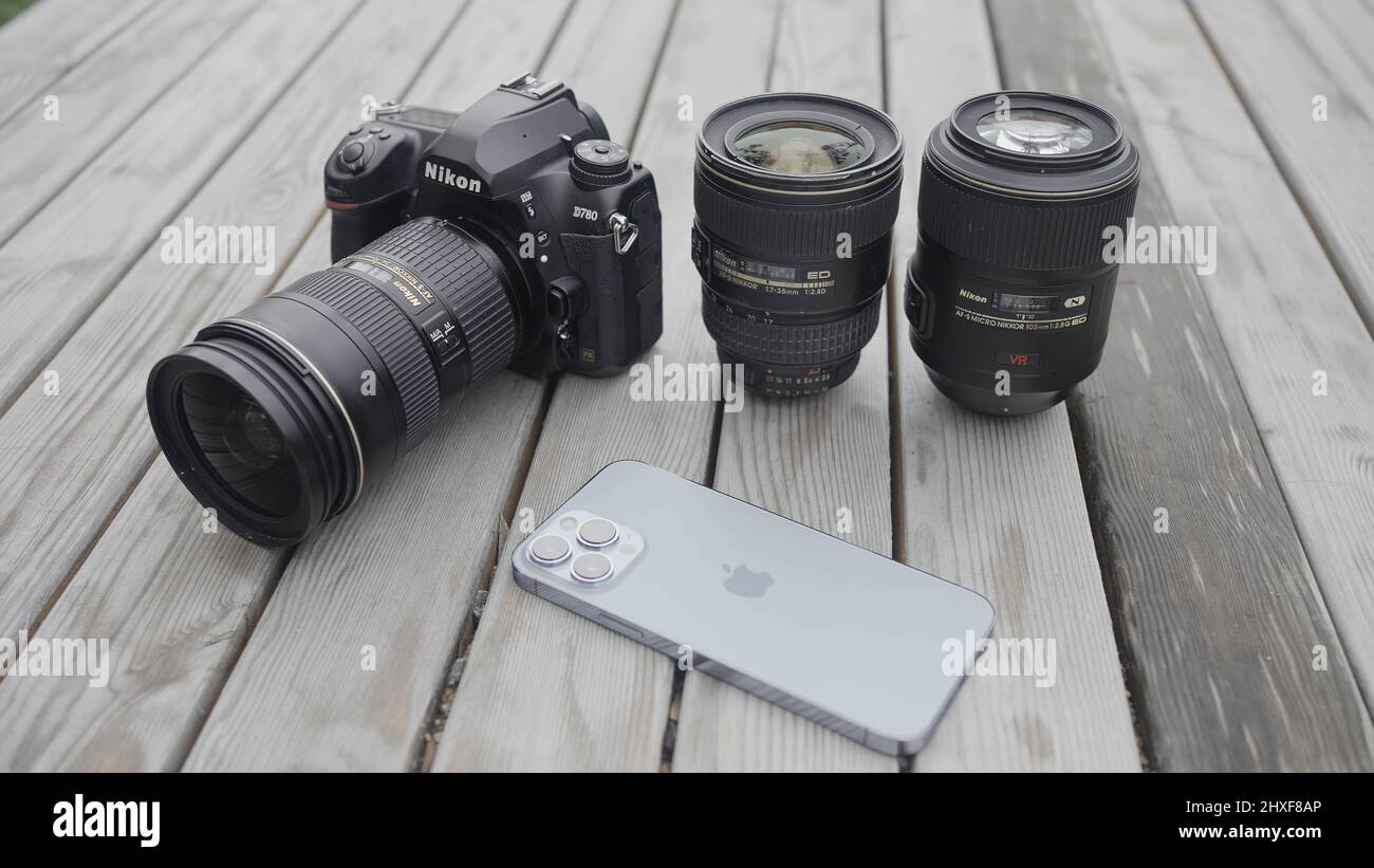 Moscow - Russia, 10.10.2021: new Nikon camera with lens and a modern Iphone 13 pro max lying outdoors on a wooden surface. Action. Professional Stock Photo