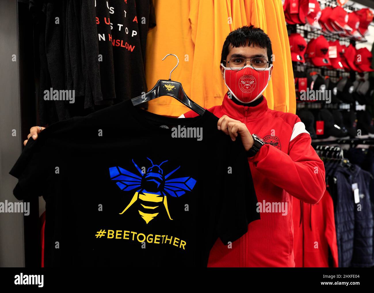 12th March 2022 ; Brentford Community Stadium, London, England;  Premier League football, Brentford versus Burnley; member of Brentford retail staff holds up a special Brentford t-shirt featuring the Brentford Bee symbol with the national colours of the Ukraine and the hashtag &quot;#beetogether&quot; Credit: Action Plus Sports Images/Alamy Live News Stock Photo