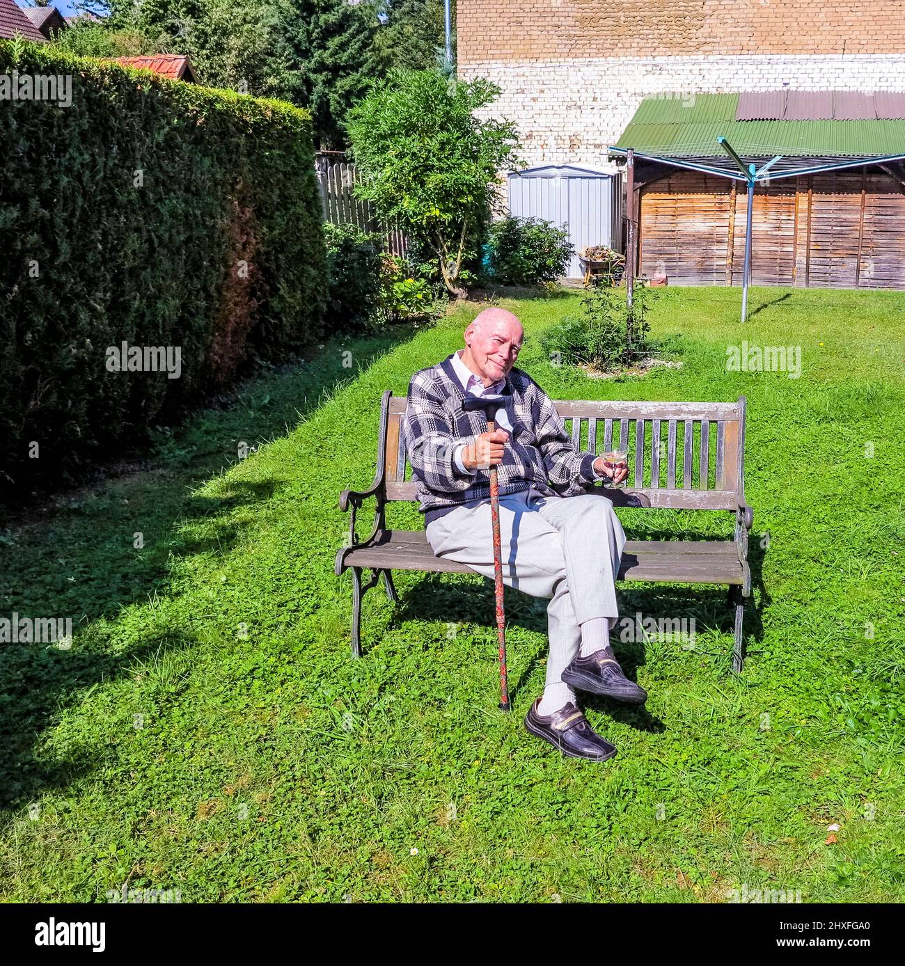 old man enjoys sitting on a bench in his garden Stock Photo - Alamy