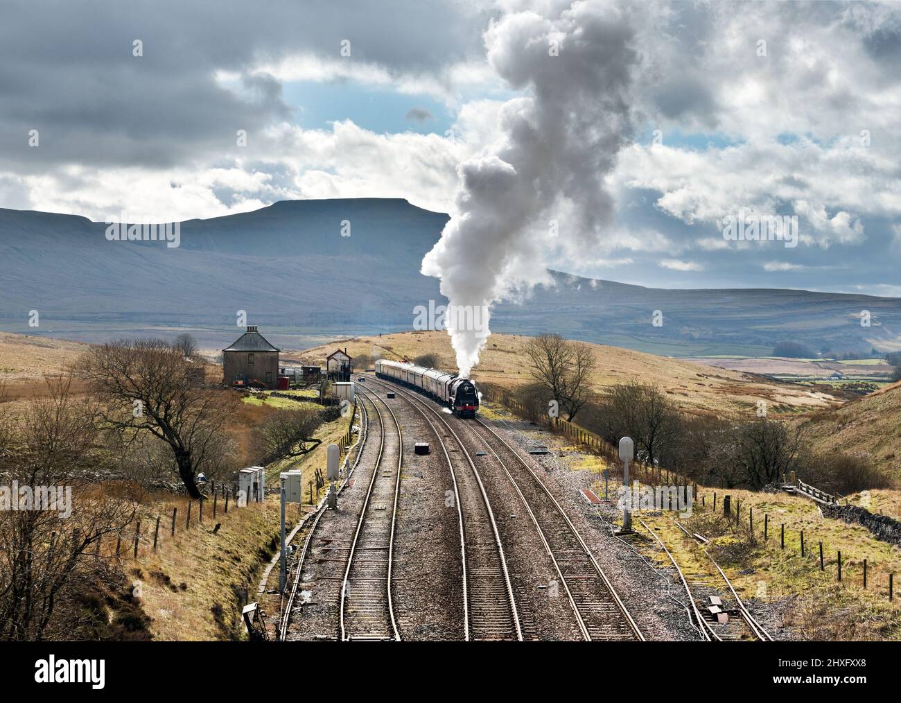 Locomotive 'The Duchess of Sutherland' with 'The Cumbrian Mountaineer', a Saturday steam special on the Settle-Carlisle railway. The train is seen at Blea Moor, after leaving the Ribblehead Viaduct bound for Carlisle. The strong back-winds carried the steam high into the air. Ingleborough peak is seen behind the train. Many people turned out to see this popular locomotive, as The Duchess of Sutherland, built in 1938, is now based in the south of England and has not been seen on the Settle-Carlisle railway line for some years. Credit: John Bentley/Alamy Live News Stock Photo