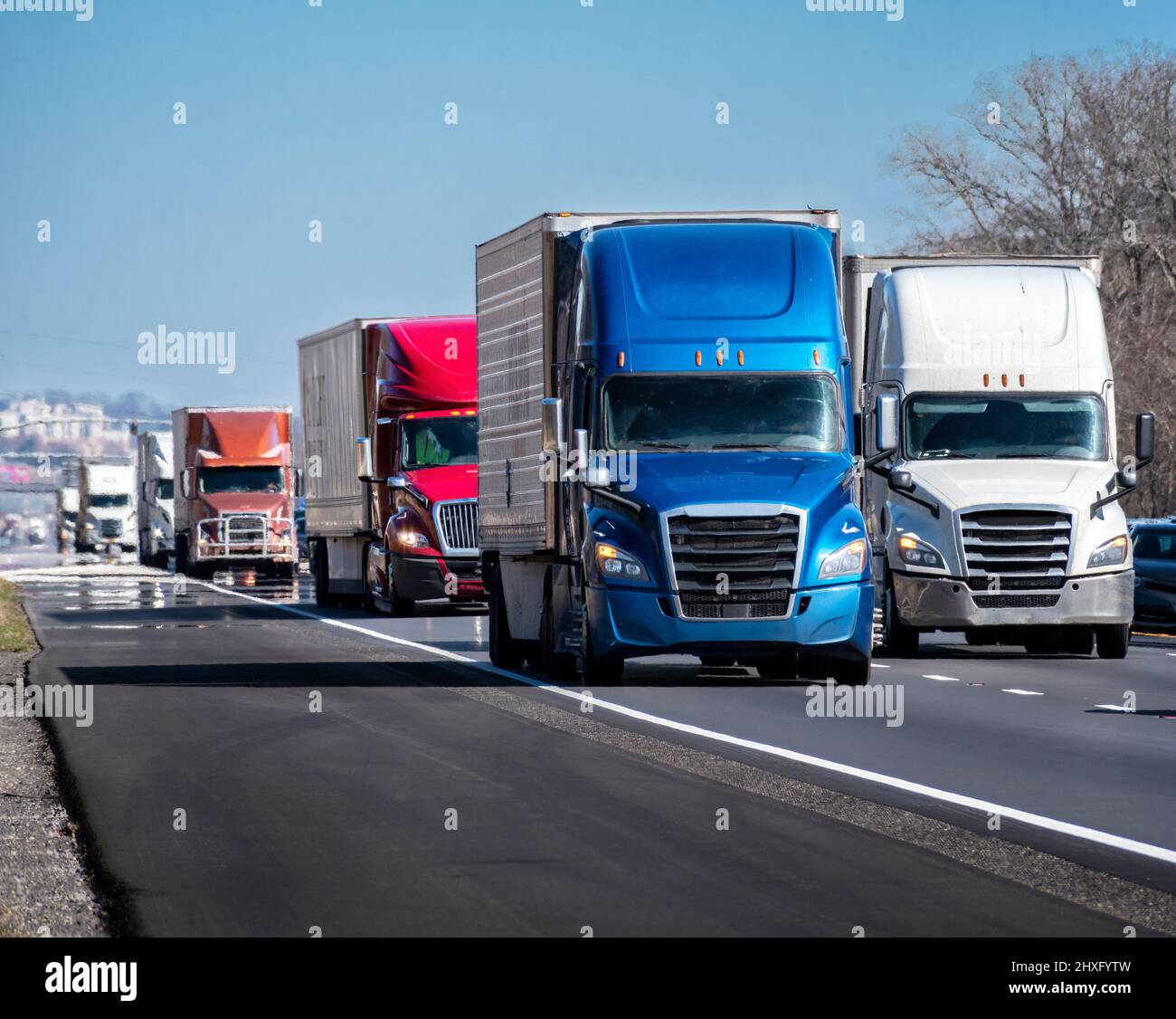 Horizontal shot of a long convoy of trucks on an interstate highway. Stock Photo