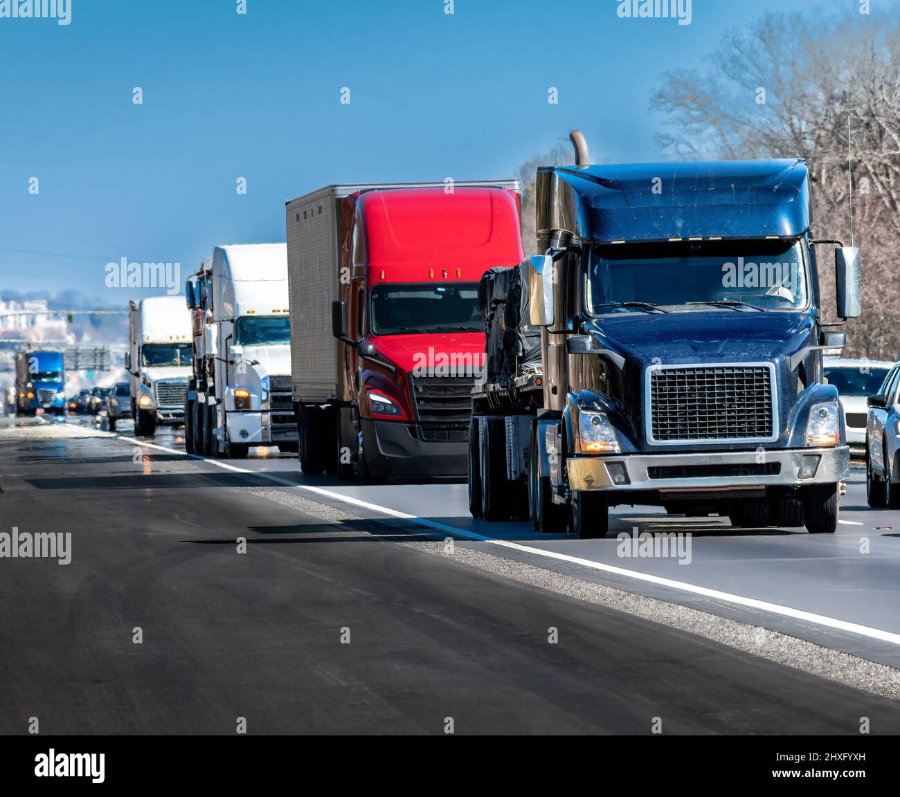 Horizontal shot of a steady stream of trucks rolling down the interstate highway. Stock Photo