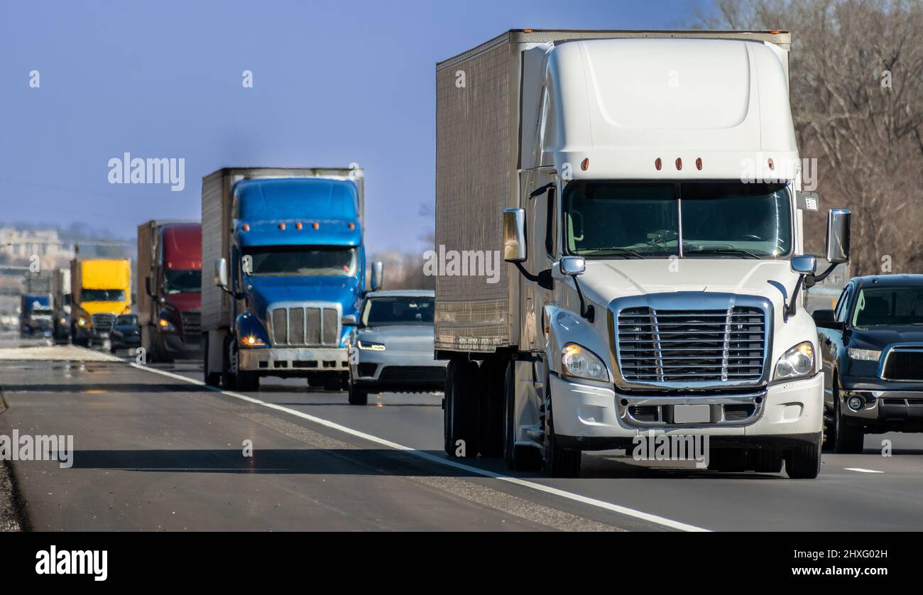 Horizontal shot of a variety of eighteen-wheel big trucks navigating the interstate. Stock Photo