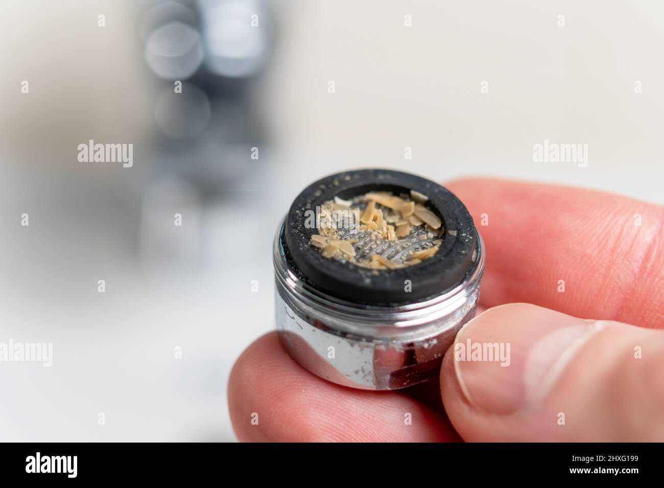 Rust scales in a clogged dirty bathroom faucet aerator closeup in hand