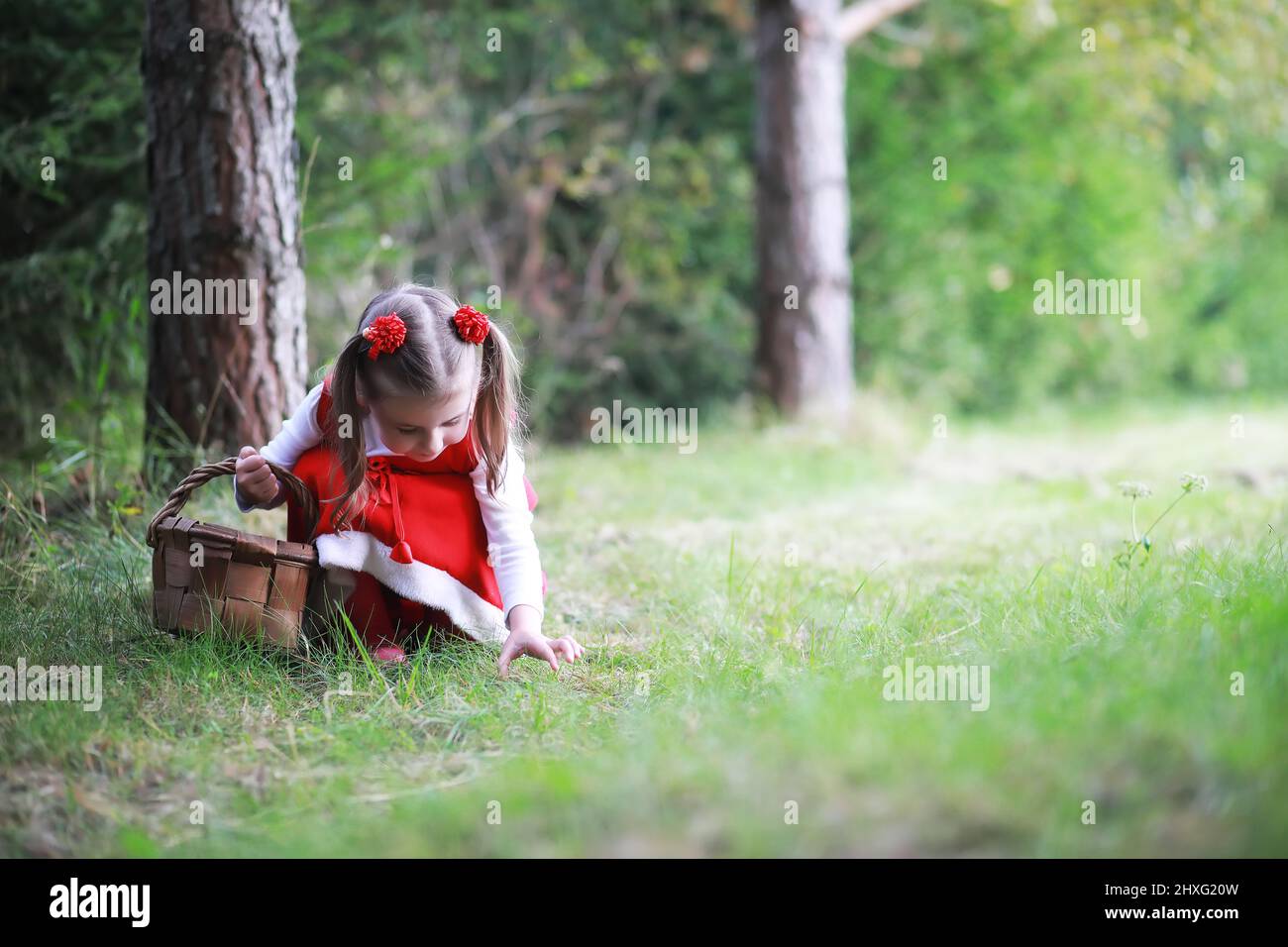 A little girl in a red hat and dresses is walking in the park. Cosplay ...