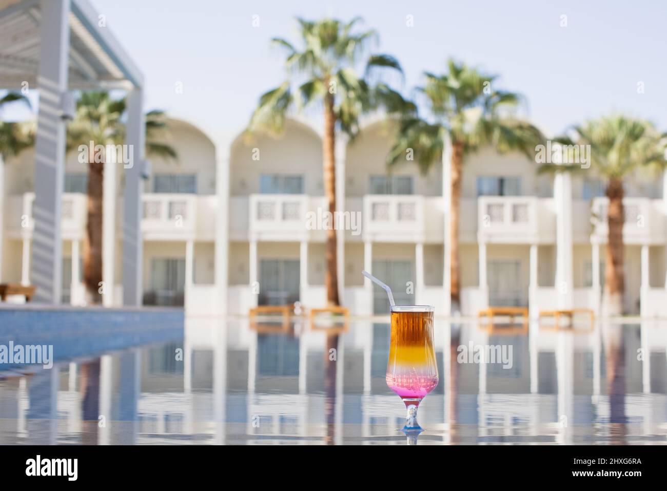 Rainbow cocktail at the edge of a resort pool. Concept of luxury