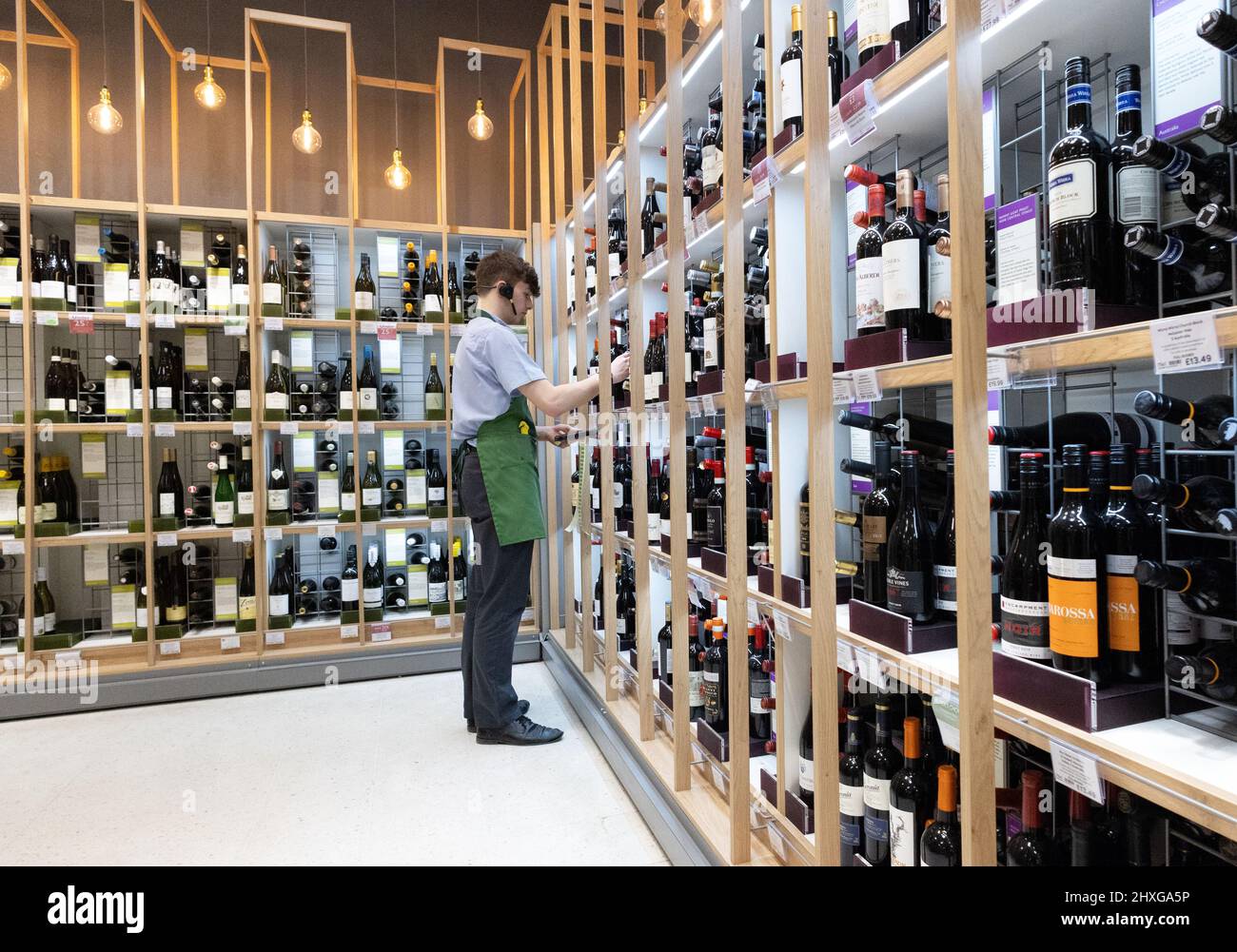 Supermarket wine department UK; a staff member working in the wine aisle, waitrose supermarket UK Stock Photo