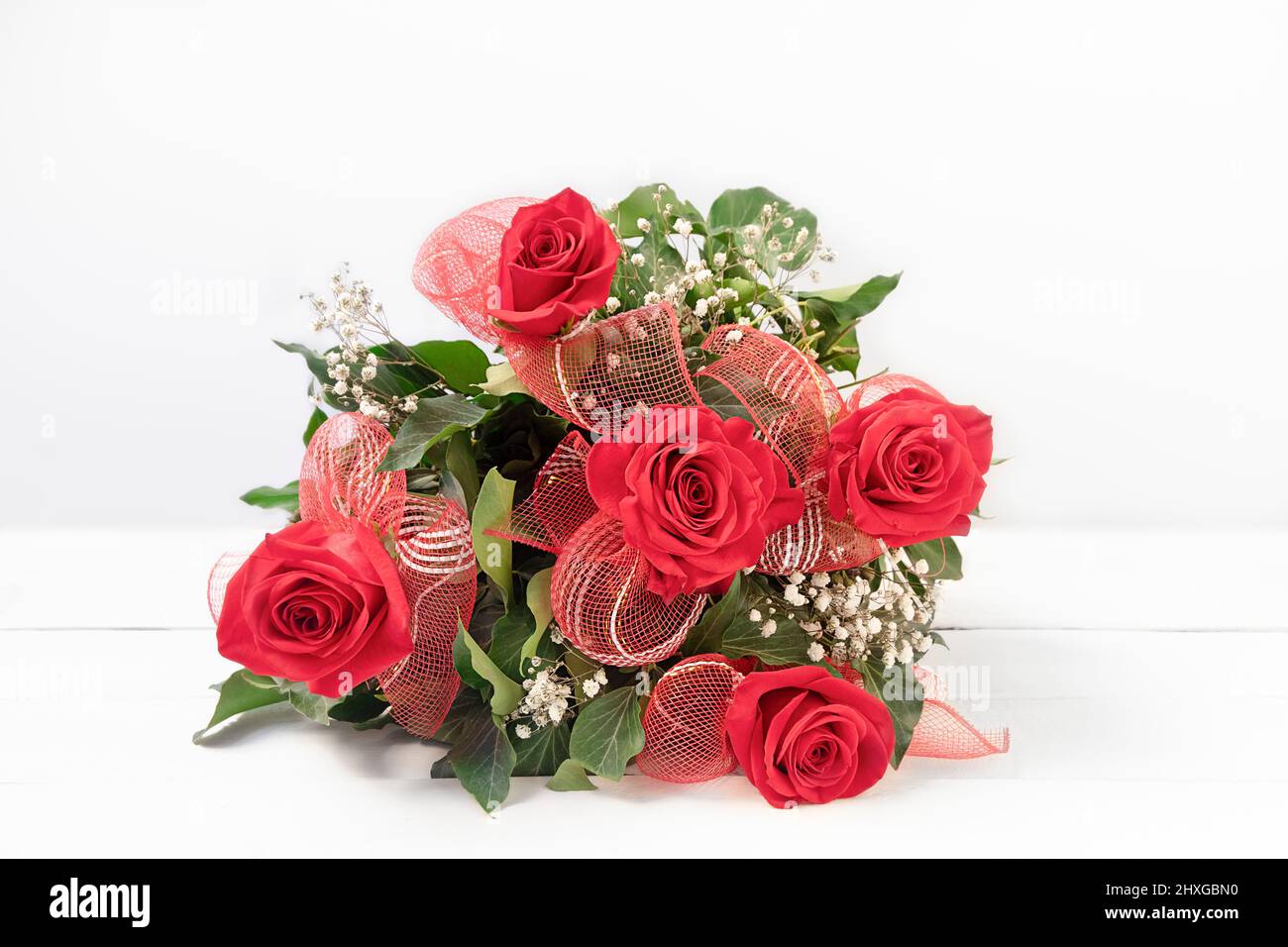 Beautiful bouquet of red roses on white wooden table. Women's day background, copy space Stock Photo