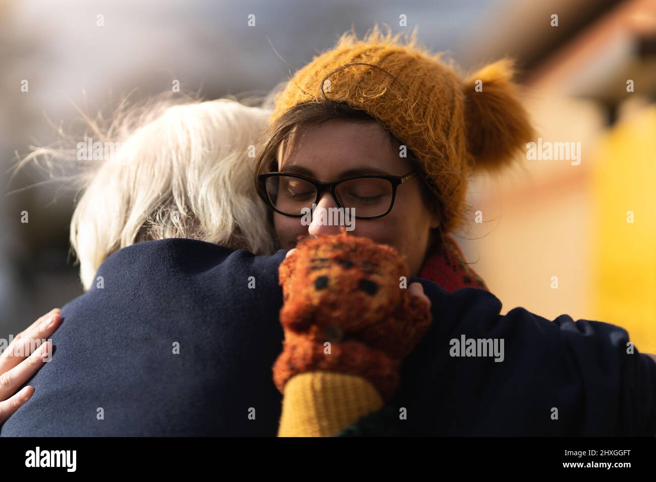 Young women hugging her grandfather after a long separation, meeting outside women wear woolly hat scarf and gloves Stock Photo