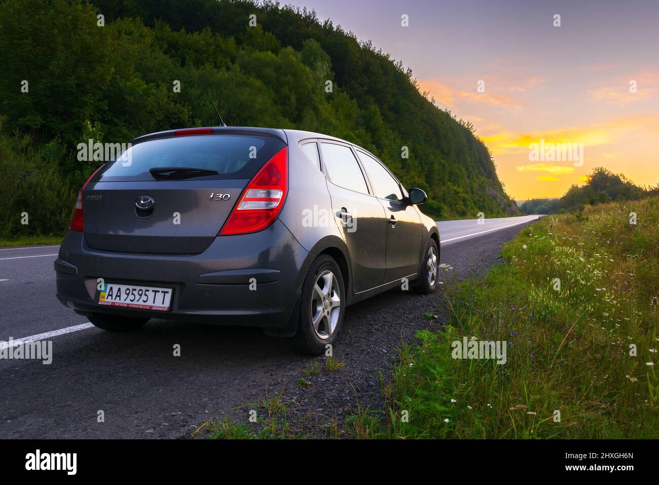 abranka, ukraine - AUG 08, 2020: hatchback on the roadside of mountain pass. wonderful countryside scenery at dawn. glowing clouds on the sky in summe Stock Photo