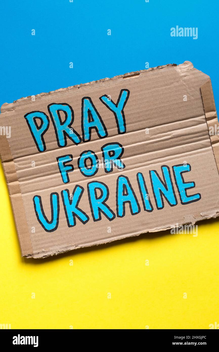 Hand drawn poster with slogan Pray For Ukraine on Ukrainian flag. Stock Photo