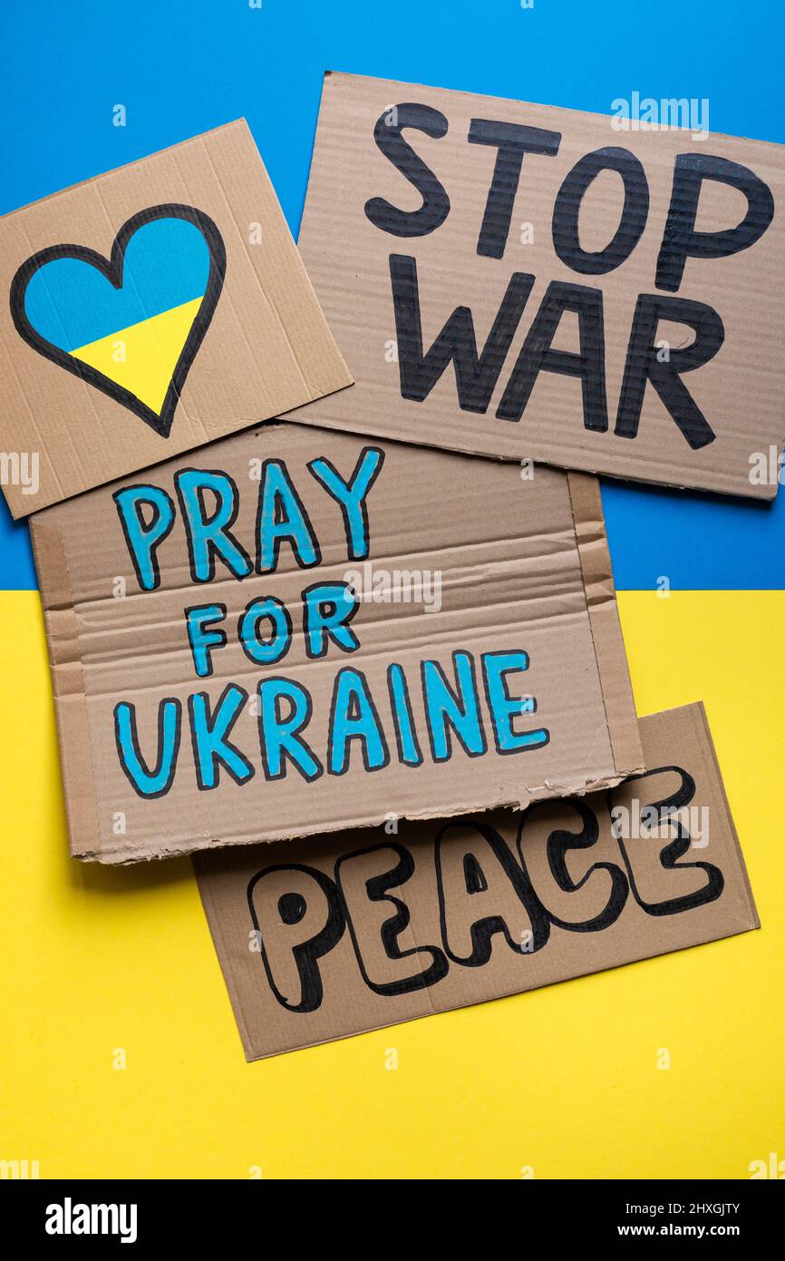 Different posters against the war between Russia and Ukraine on the Ukrainian flag. Stock Photo
