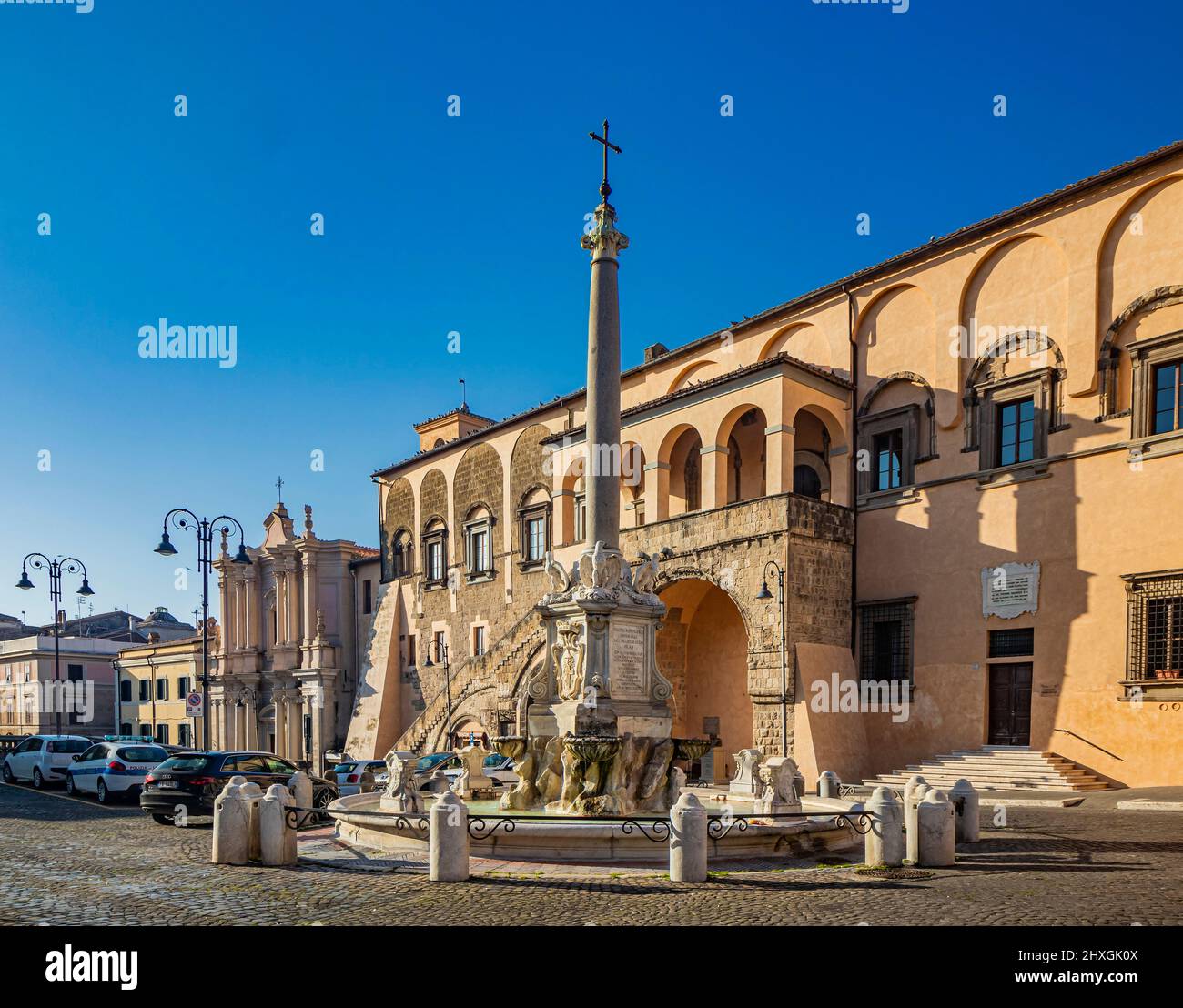 Feb.6, 2022 - Tarquinia, Viterbo, Lazio, Italy - The main square of the village. The circular fountain with the obelisk and the cross. The town hall i Stock Photo