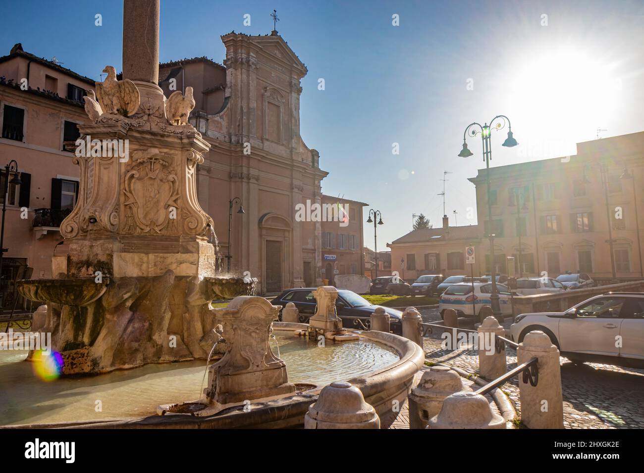Feb. 6, 2022 - Tarquinia, Viterbo, Lazio, Italy - Circular fountain with the obelisk and the cross. The Church of San Leonardo. Backlight photography, Stock Photo