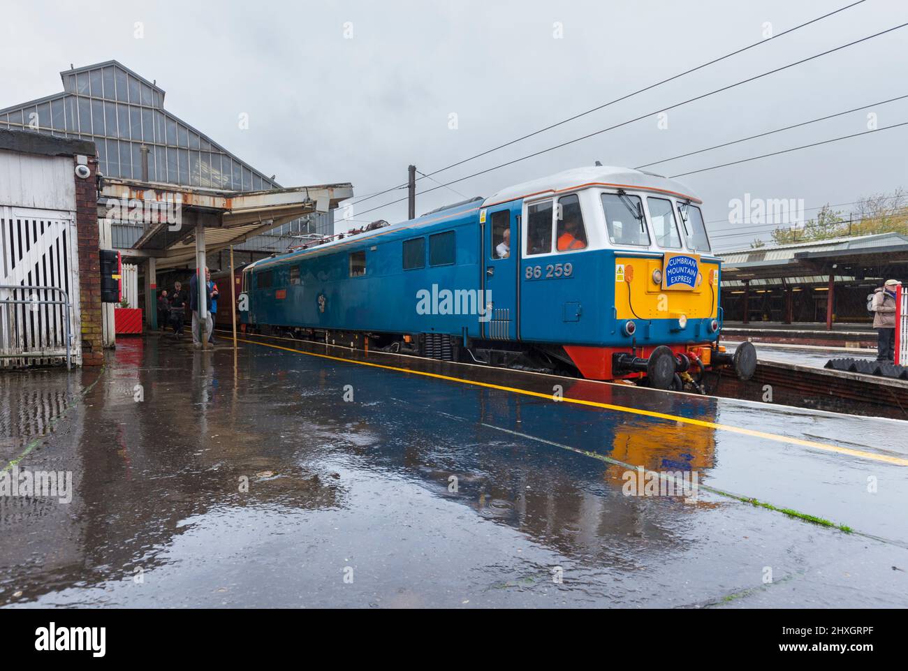 Preserved class 86 electric locomotive 86259 hauling a West Coast railways charter train at Preston railway station reflected in the wet platform Stock Photo