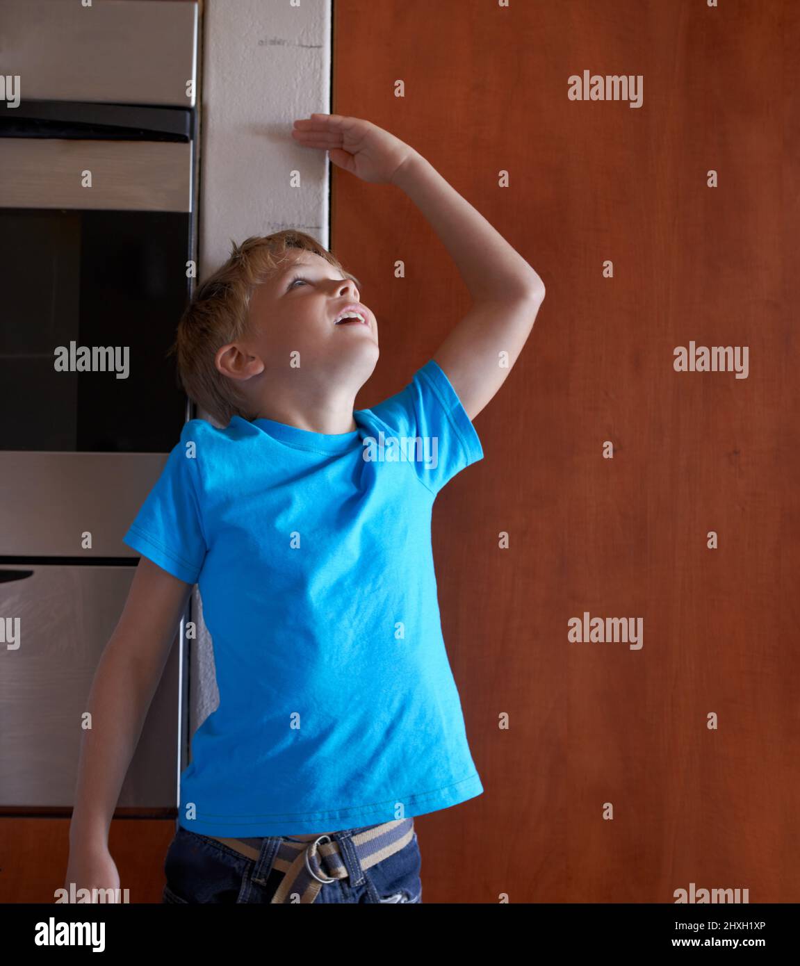 Hes growing fast. A young boy measuring his height at home. Stock Photo