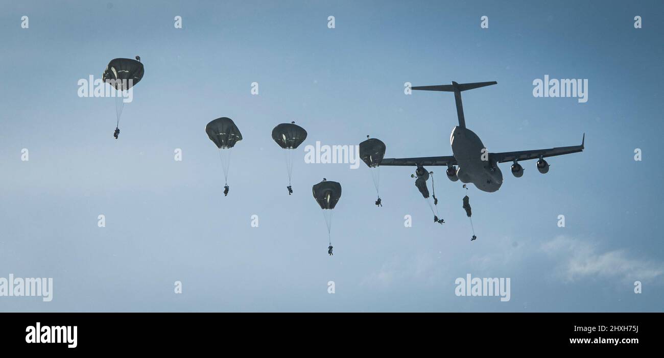 Members of the United States Army Alaska along with members of the 3rd Battalion, Royal 22e Régiment Canadian Army parachute to the ground after jumping out of C-130 and C-17 aircrafts over the training area of Fort Greenly in Alaska USA during Exercise Joint Pacific Multinational Readiness Center 22-02 on March 12, 2022.  Please Credit Master Sailor Dan Bard Canadian Forces Combat Camera Stock Photo