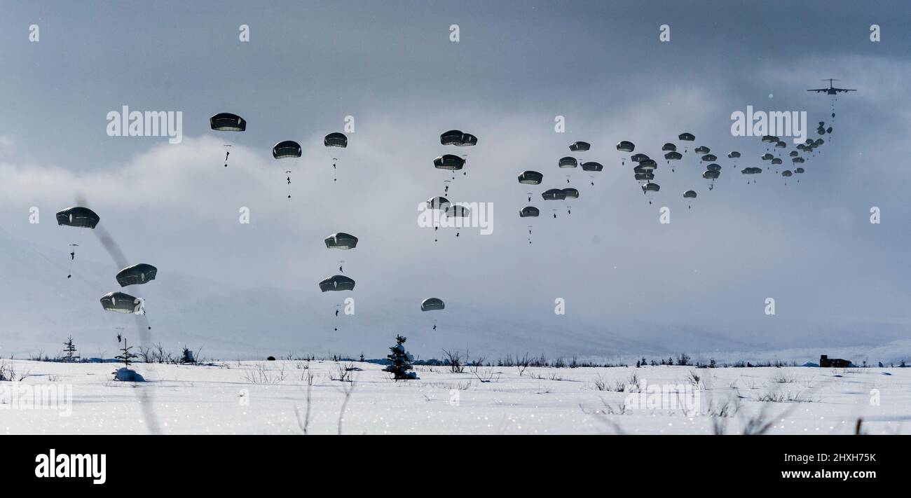 Members of United States Army Alaska along with members of the 3rd Battalion, Royal 22e Régiment Canadian Army parachute to the ground after jumping out of C-130 and C-17 aircrafts over the training area of Fort Greenly, Alaska during Exercise Joint Pacific Multinational Readiness Center 22-02 on March 12, 2022.  Photo Credit: Master Sailor Dan Bard Canadian Forces Combat Camera Stock Photo
