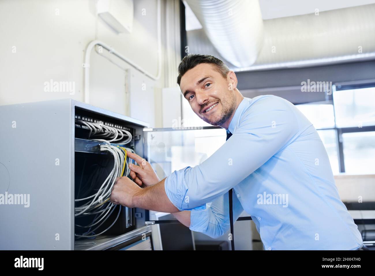 Youll be online in one more minute. Portrait of a smiling computer engineer working on a server. Stock Photo