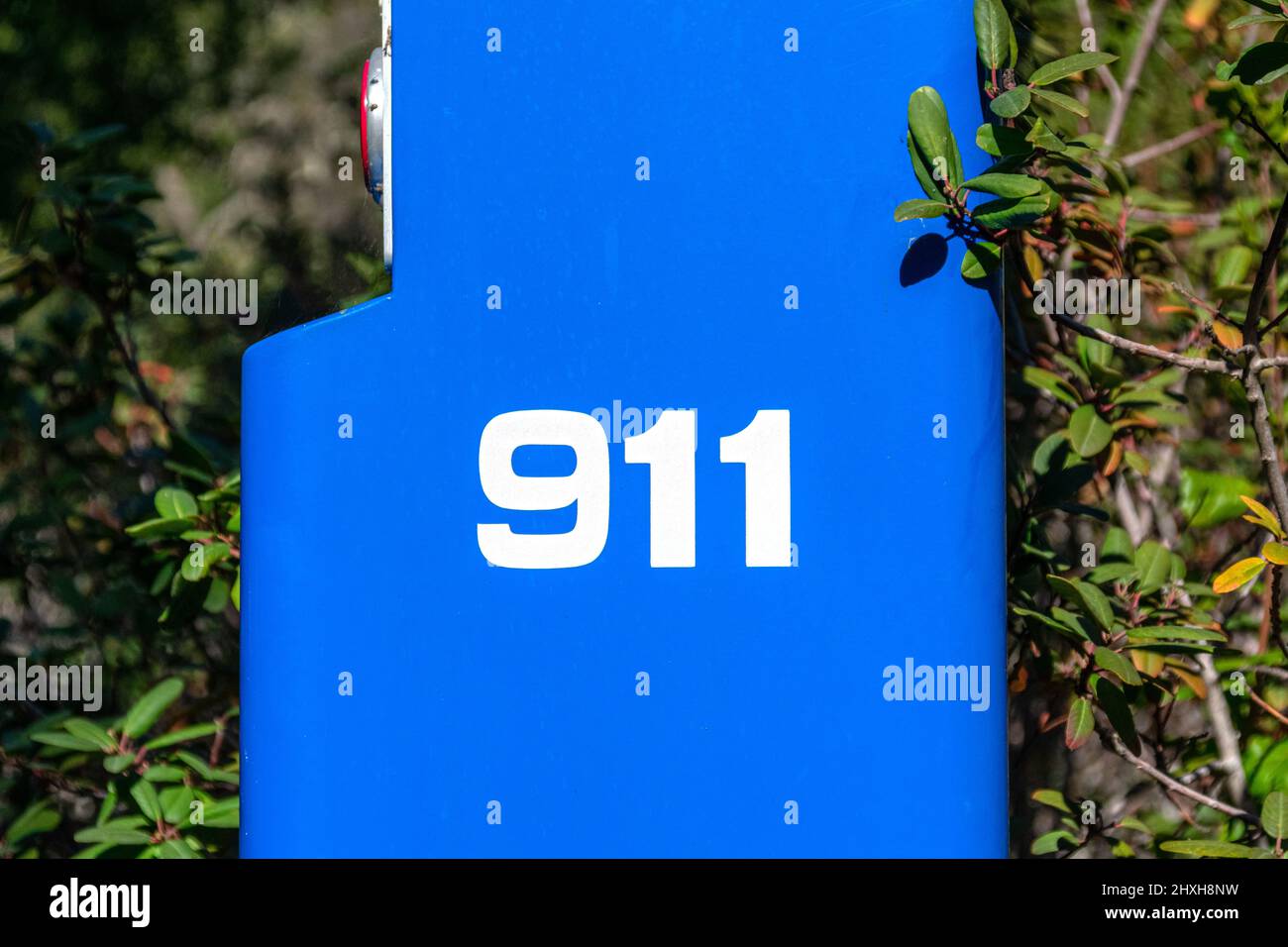 911 sign on blue light phone and alarm system, call box is a symbol of security in city park, corporate or hospital campus, on school grounds. Stock Photo