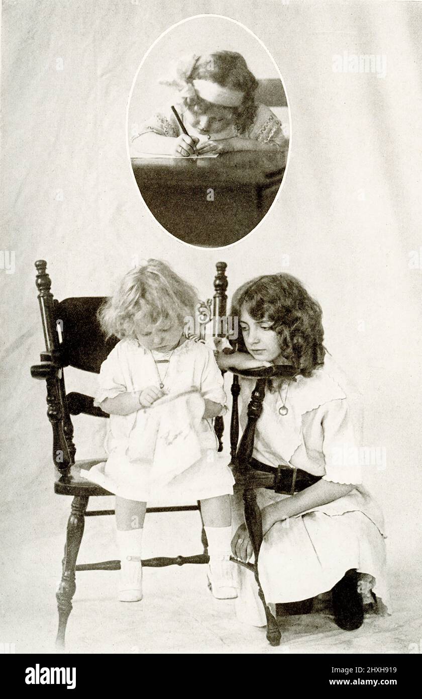 The caption for this 1917 image reads: 'Pleasant Pictures of Child Life.' It shows an older girl watching a young child do stitch work . In the inset above is a young child writing. Stock Photo
