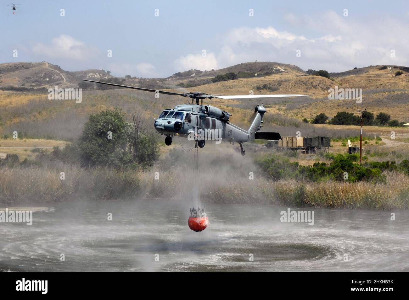 US Navy MH60S fills Bambi Bucket aboard MCB Camp Pendleton; California during firefighting exercises with Cal Fire. Stock Photo