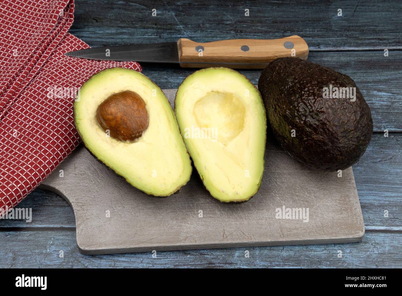whole and cut avocado on a wooden board Stock Photo - Alamy