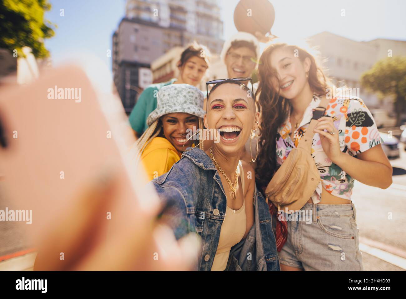 Friends taking a selfie together in the sun. Group of generation z friends having fun while hanging out together in the city. Multiethnic young people Stock Photo