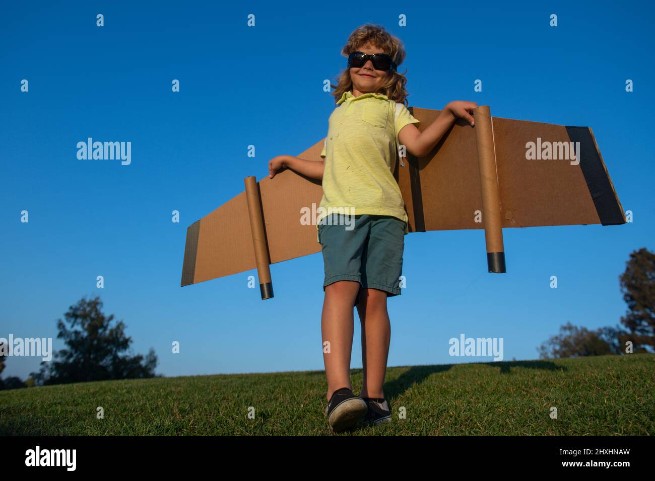 Caucasian kid playing with toy plane on sky background outside on ...