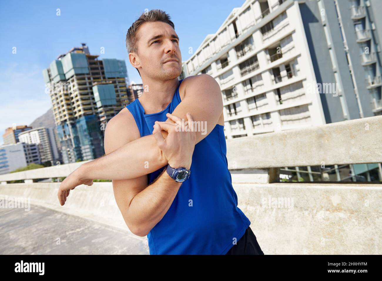 Stretching is important before exercise. Young runner stretching his shoulder before a run. Stock Photo
