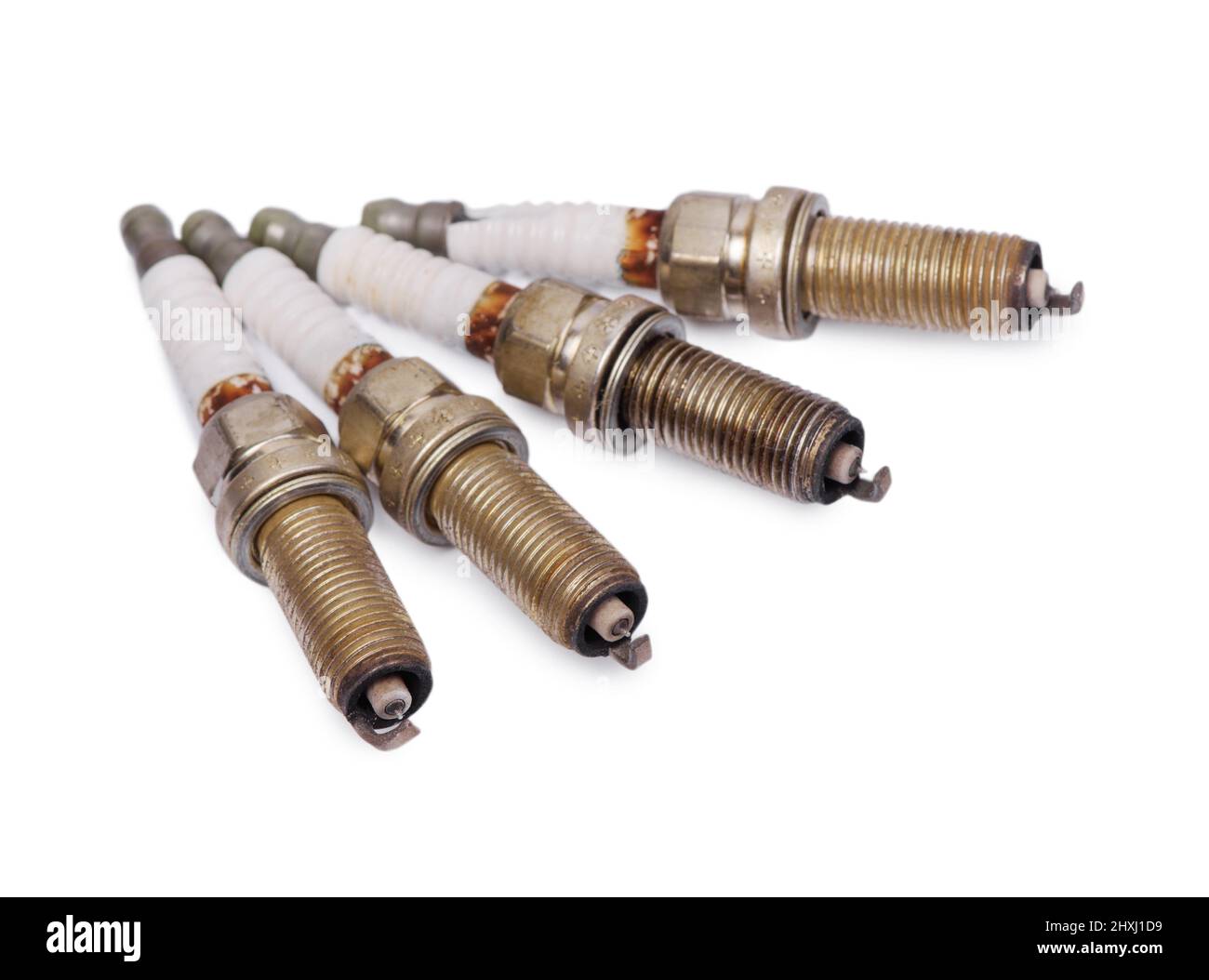Four old used spark plugs isolated on white background Stock Photo