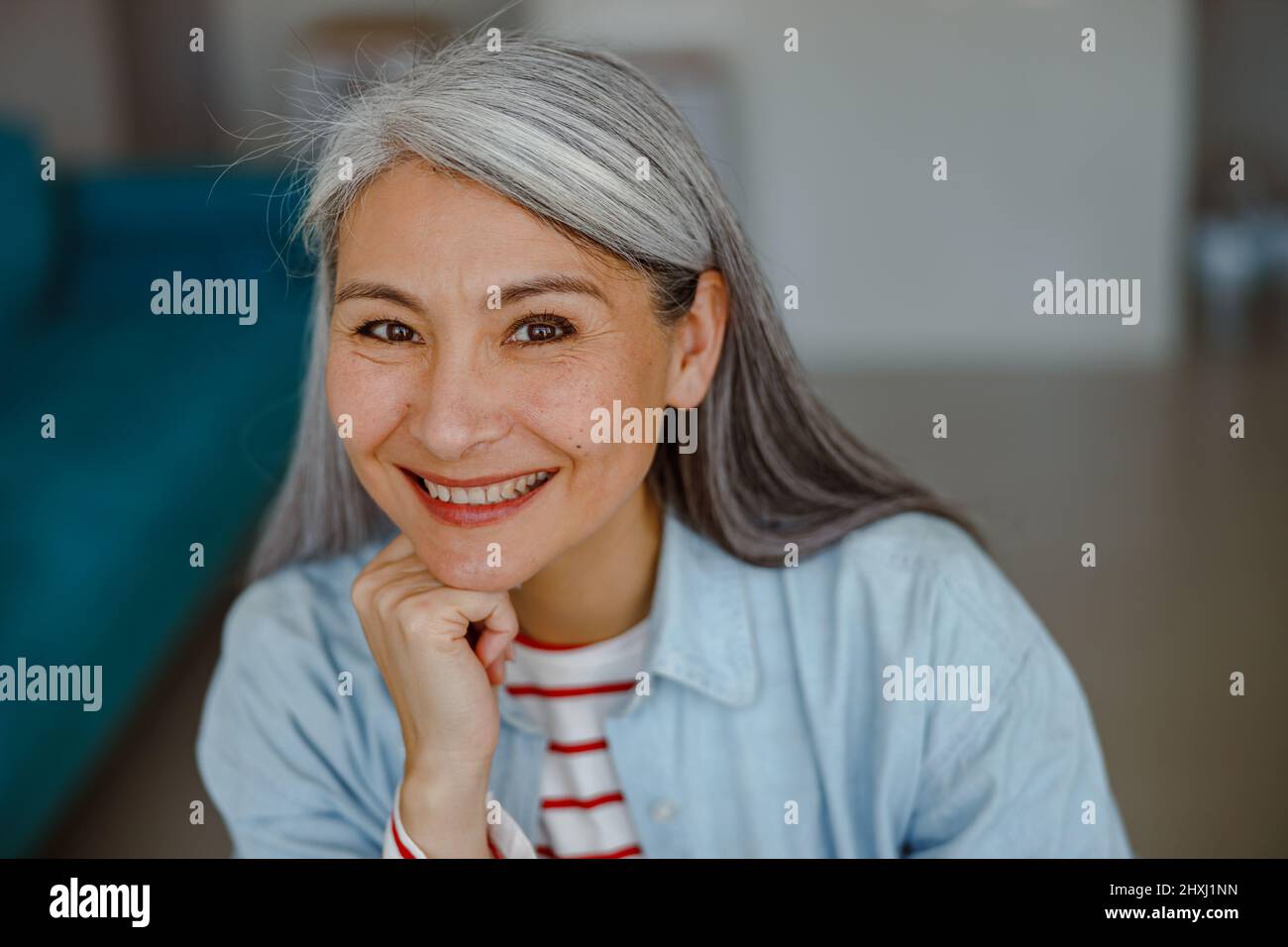Cheerful woman propping up head with hand and smiling Stock Photo