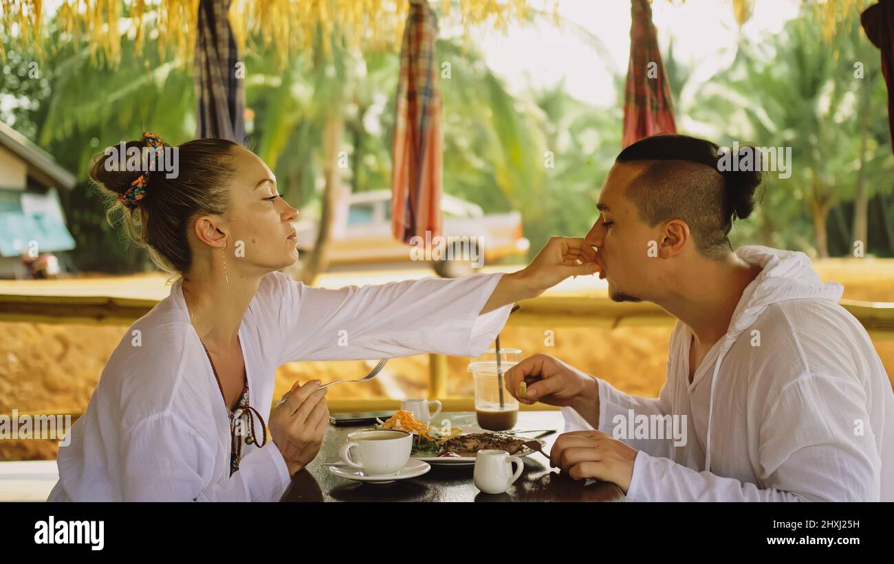 Attractive young man and woman eat and drink tasty beverages spending