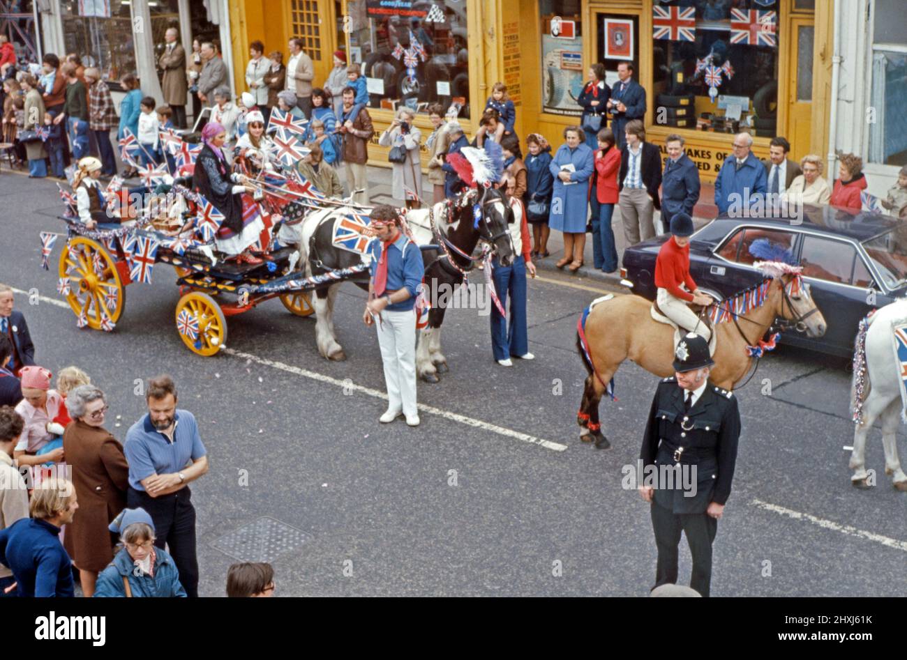 A parade held on 6 June 1977 to celebrate the Silver Jubilee of Queen Elizabeth II. This took place in Sheen Lane, East Sheen in London’s SW14, England, UK. Here a gypsy-themed horse and cart passes down the street. Union Jack flags of all sizes are on show. The twenty fifth anniversary of the Queen’s coronation was on 6 February 1977 but 7 June was designated for a major official and unofficial celebration day across the country. This image is from an old amateur colour transparency – a vintage 1970s photograph. Stock Photo