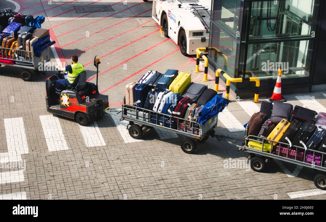 Motorised baggage cart carrying luggage at an airport runway Stock Photo