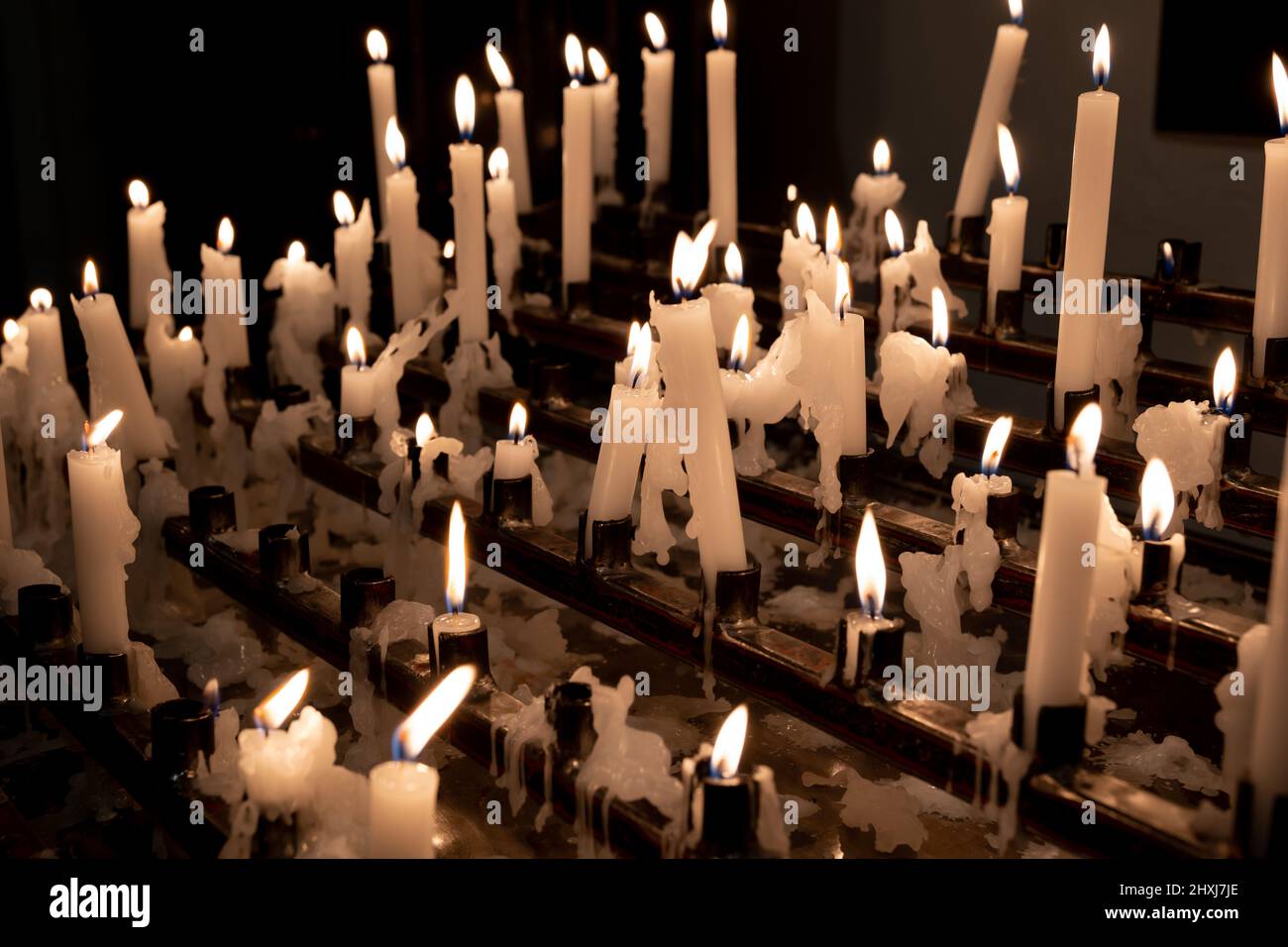 Votive candles or prayer candles rack lit in a church, Christian tradition. Stock Photo