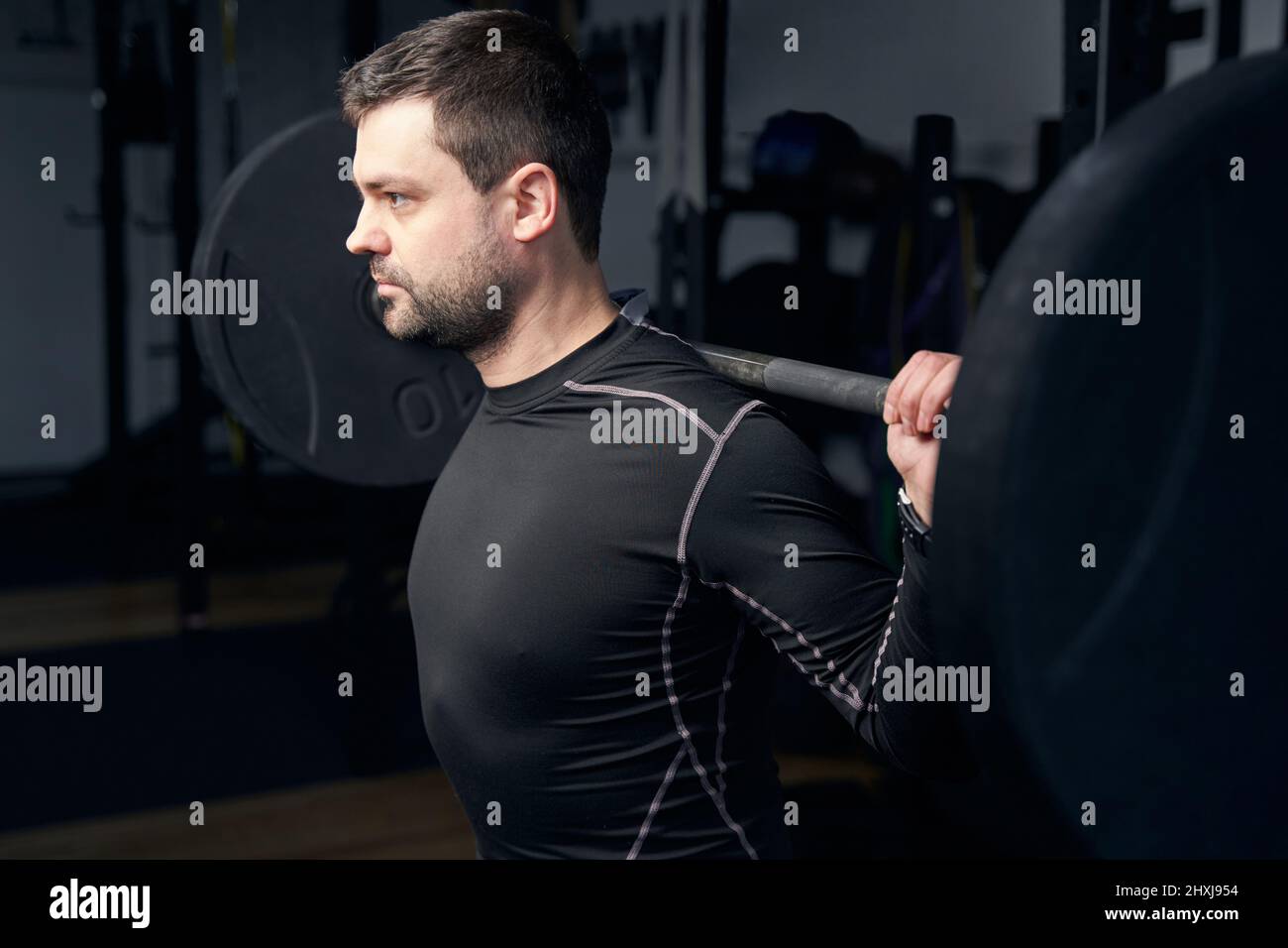 Athletic man doing exercise with barbell in gym Stock Photo