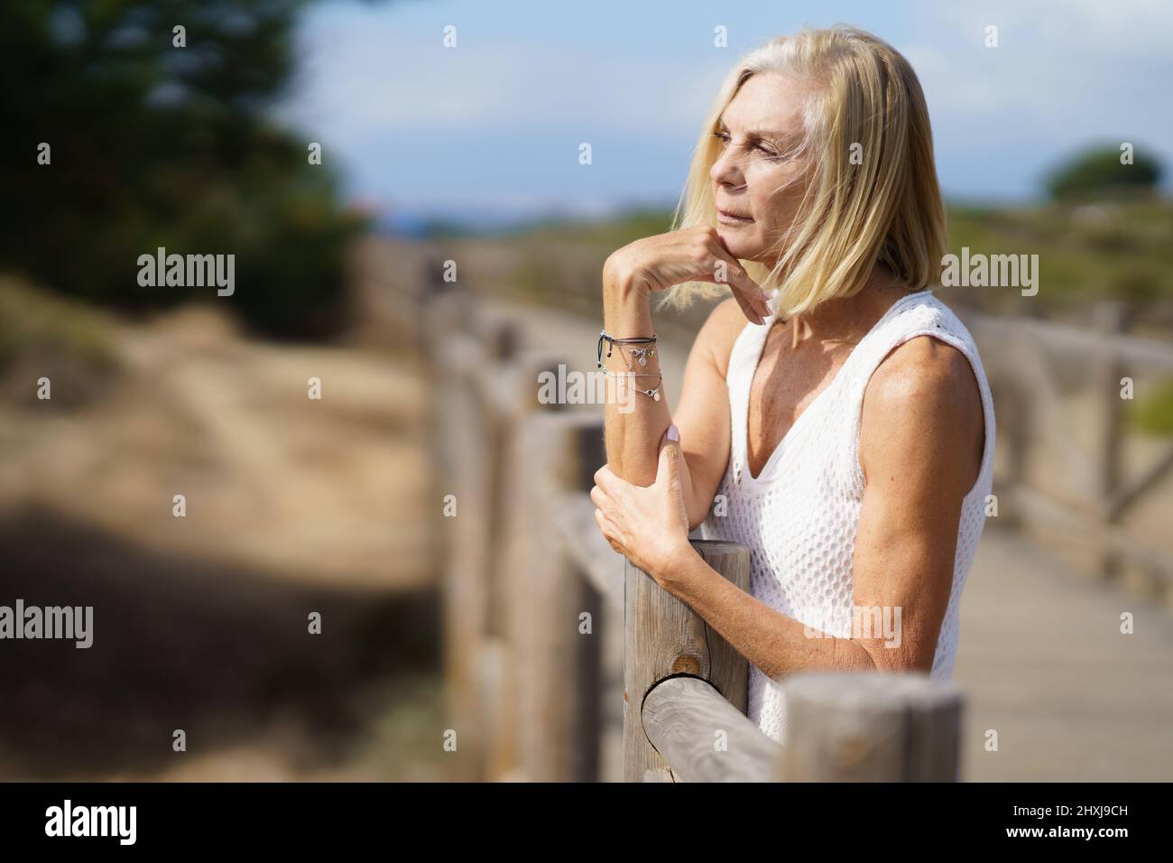 Thoughtful senior woman on boardwalk on beach Stock Photo