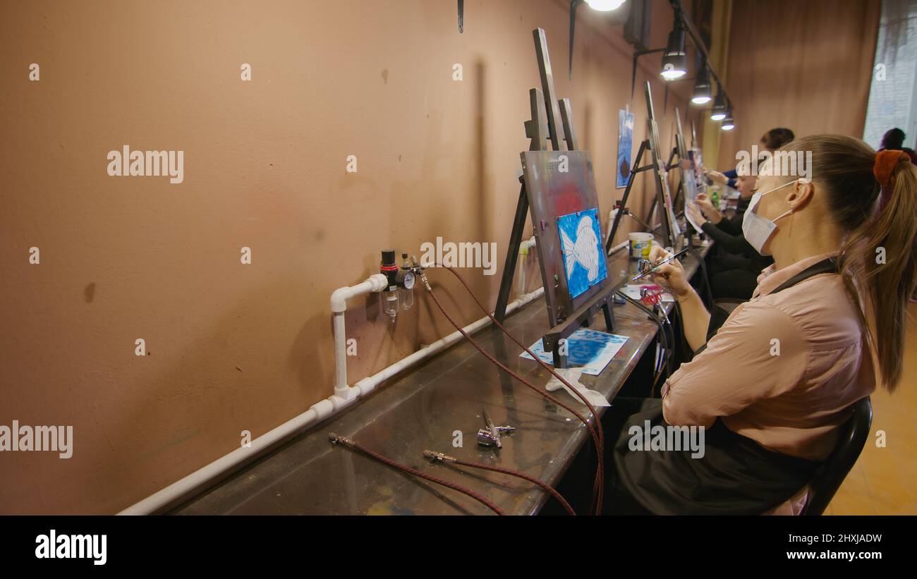 Woman artist learns to paint with airbrush with acrylic dye, paper and