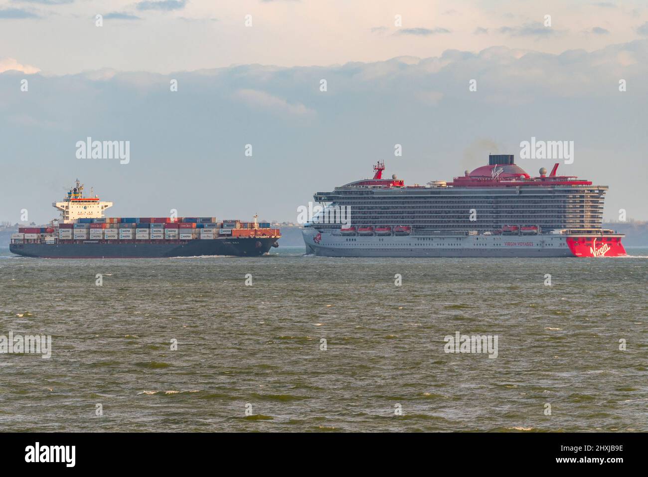 Valiant Lady, new cruise ship for Virgin Voyages seen heading out to sea on Thames Estuary after launch party at Tilbury. Passing container ship Stock Photo