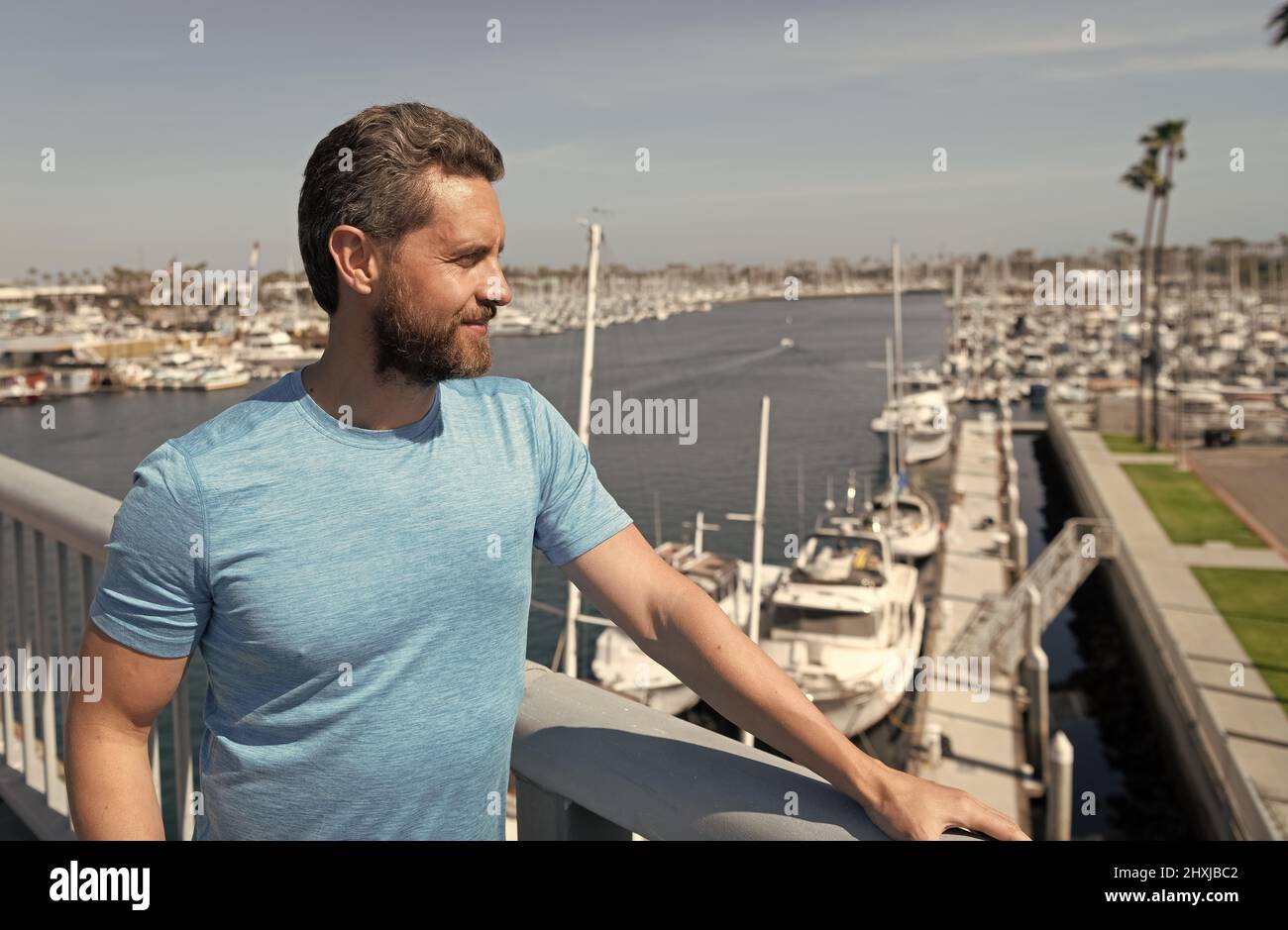 Handsome man vacationer stand at bridge railing over river summer outdoors, vacation Stock Photo