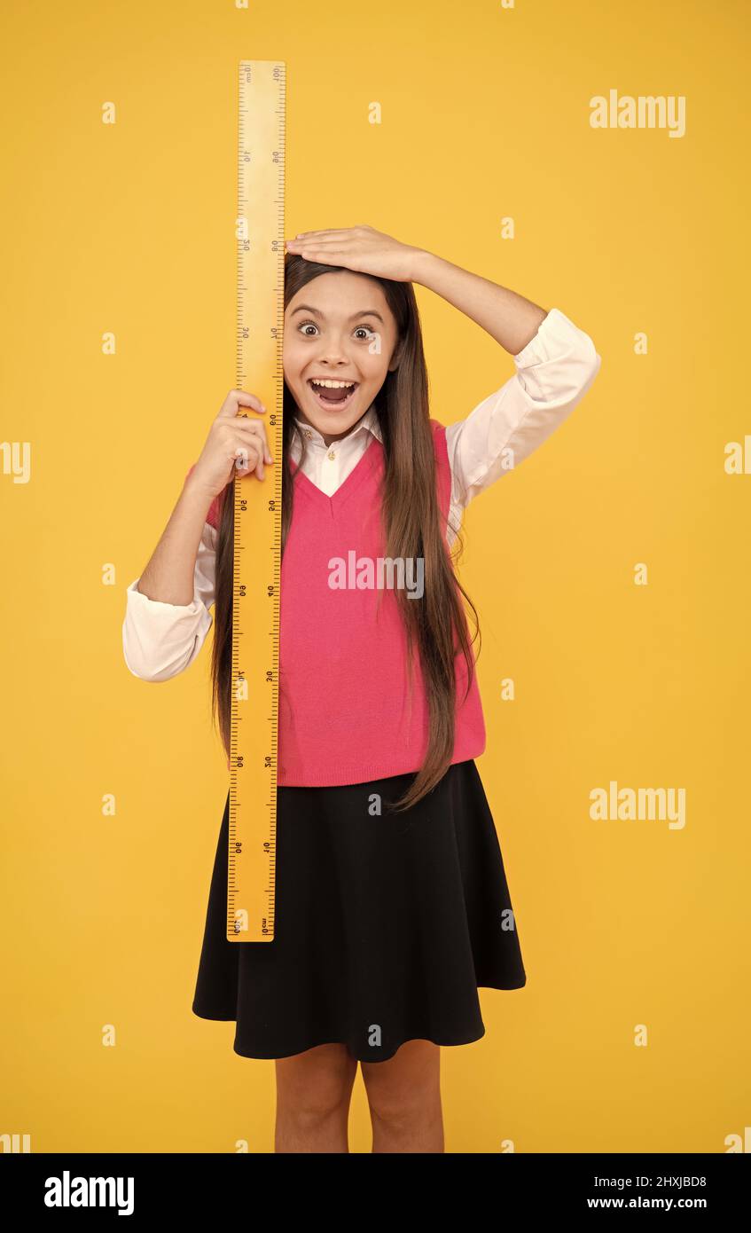 surprised kid girl use ruler to measure the height, measurement Stock Photo