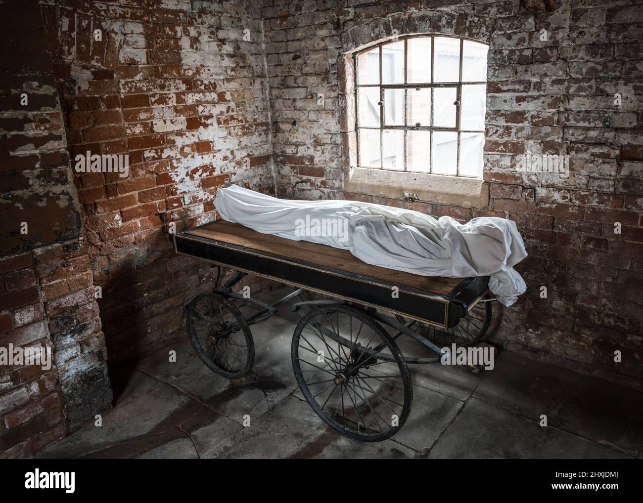 Dead body cadaver wrapped in white sheets on trolly bed ready for collection for autopsy then burial. Stock Photo