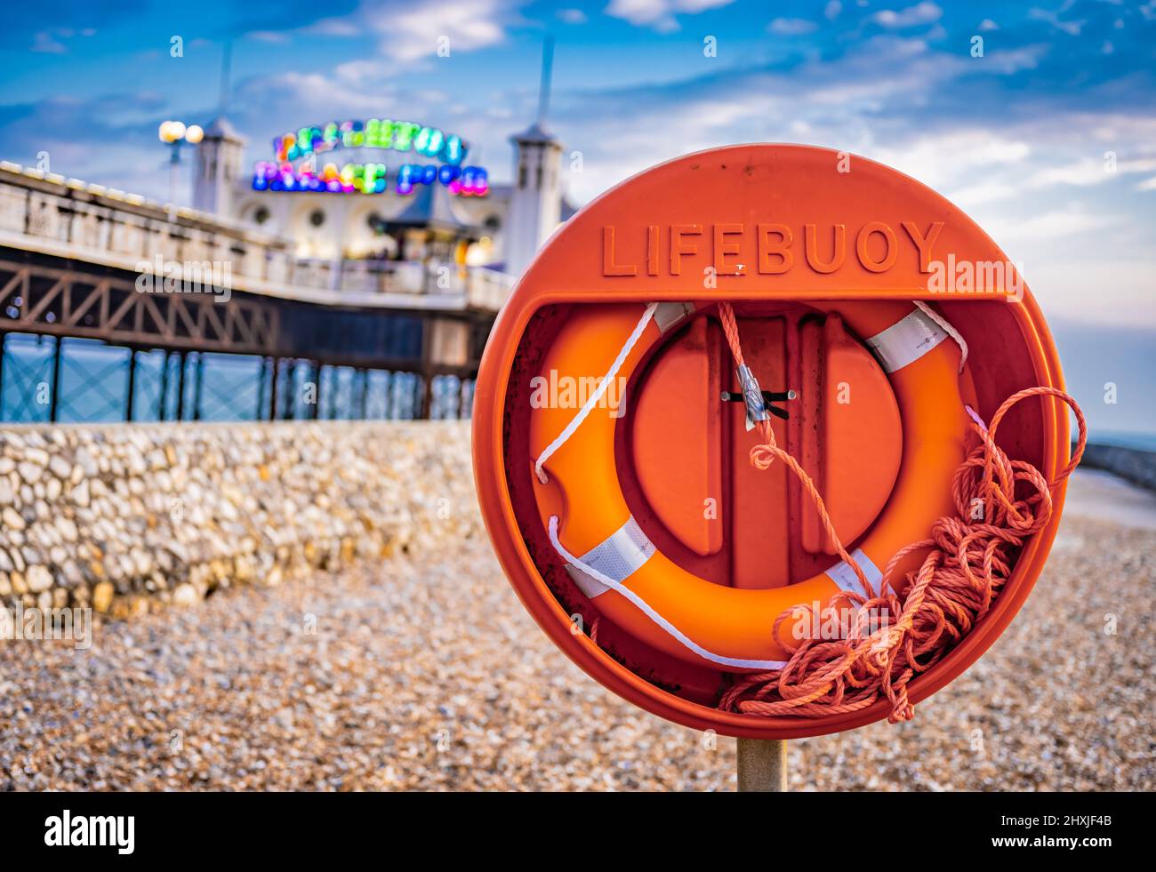 Dusk picture of Brighton Palace Pier, with a vivid bright orange life bouy in the foreground, in Brighton, East Sussex Stock Photo