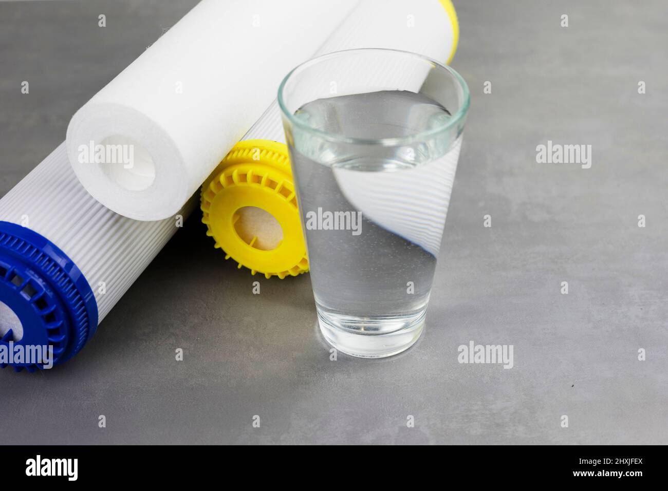 A glass of clean water next to the water purification filter. The concept of a household filtration system. Stock Photo